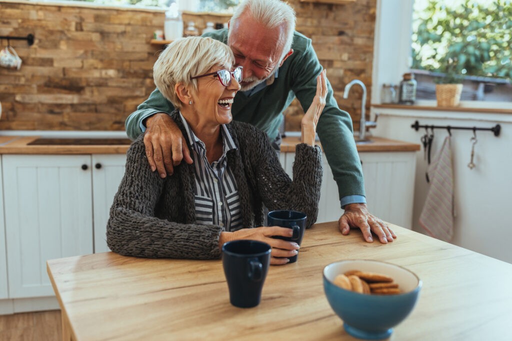 An older couple laughing together in their kitchen