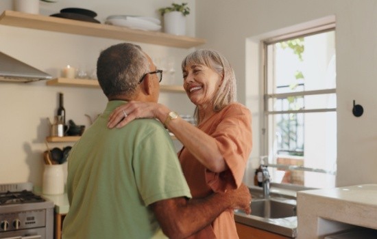 An older couple dancing together at home.